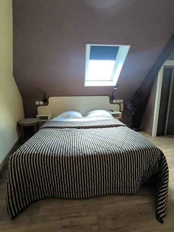 Chambre sous les combles avec fenêtre de toit et grand lit à l'Hotel De France